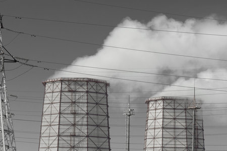 Toxic gray smoke is released from the cooling tower into the atmosphere and pollutes the environment, air and atmosphere. Operation of the industrial heat and power plant.の写真素材
