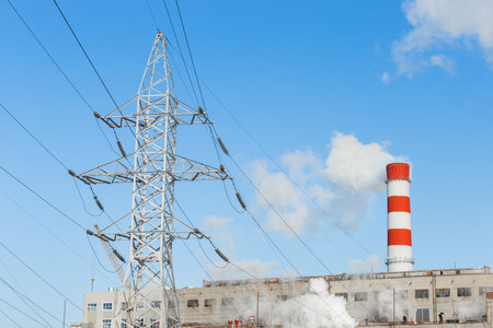 The pipe of the industrial plant emits smoke into the atmosphere and air. Pollution of the environment and ecology. Thermal power plant power lines high voltage.の写真素材