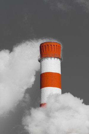 Pollution of the environment, ecology and air. Withdrawal of combustion products of soot, smoke and gases from the pipe of an industrial plant into the atmosphere against the background of a gray sky.の写真素材