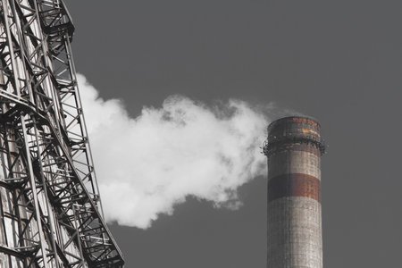 Pollution of the environment, ecology and air. Withdrawal of combustion products of soot, smoke and gases from the pipe of an industrial plant into the atmosphere against the background of a gray sky.の写真素材