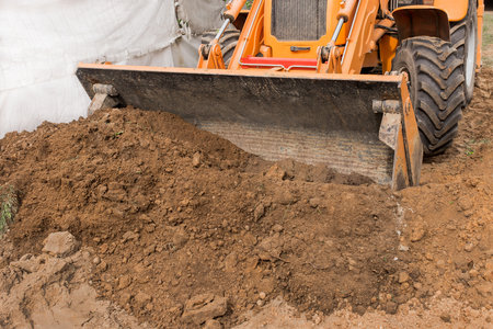 Excavator or bulldozer bucket flattens the ground or road in the industrial zone or construction site.の写真素材
