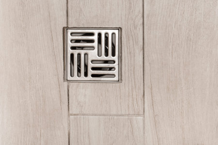 Metal hole for flushing water in a bathroom shower floor drain tile stall, top view.