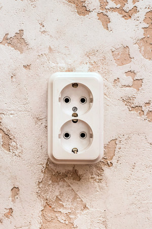 White double power socket on plaster wall in modern room interior.