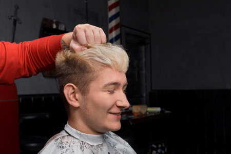 Smiling guy handsome young European appearance with closed eyes portrait white hair hairdresser client.の写真素材