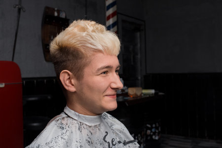 Young satisfied guy caucasian hairdresser customer with white hair portrait in barbershop.の写真素材