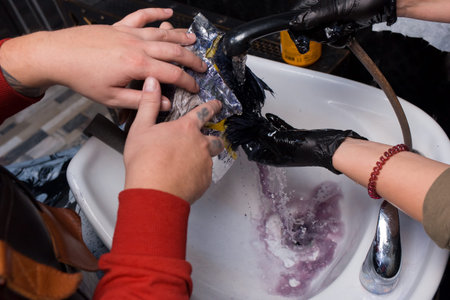 The hands of the employees of the salon and barbershop in the process of washing the client's head with water over the sink professionally work, quality services.の写真素材