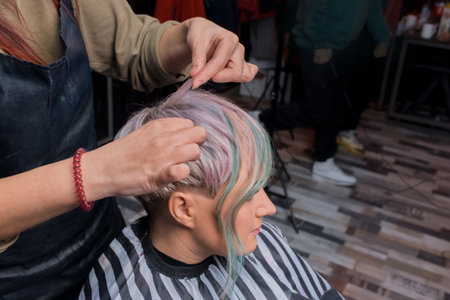 The hands of the girl of an experienced hairdresser comb her hair with a stylish fashionable hairstyle color creative coloring bob in the salon.の写真素材