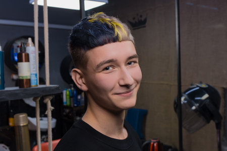 Satisfied young handsome guy of Caucasian appearance salon client with stylish fashionable hairstyle crop creative hair coloring.の写真素材
