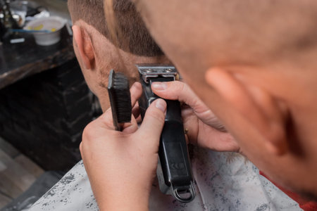 The hands of a barber of an experienced man, close-up cut the back of the client's head with a...