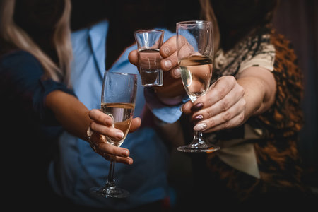 Hands of girls and men clinking glasses and a glass of alcohol close-up of the party.の写真素材