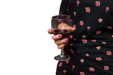 Girl with pink manicure in dark dress with flower pattern holding a glass of red wine on white isolated background.の写真素材