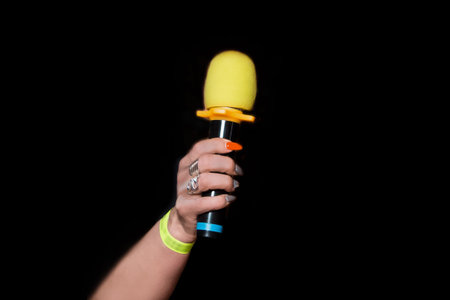 Female person hand close-up holding microphone professional karaoke singing equipment tool on black...