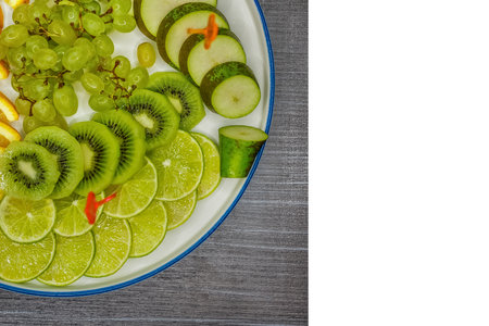 Fruit plate on table with grapes, kiwi, lime, pear and orange, sliced pieces on a white background, isolated.の写真素材