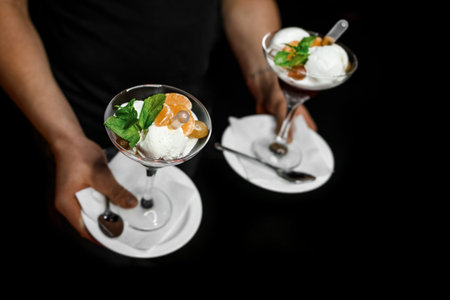 The person's hand holds 2 glasses of ice cream with a beautiful serving and decorated with a sweet,...