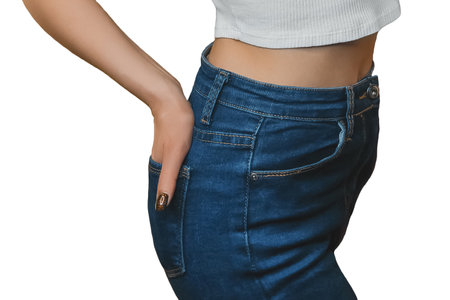 Young slim girl posing with her hand in the back pocket of blue jeans on an isolated background.の写真素材