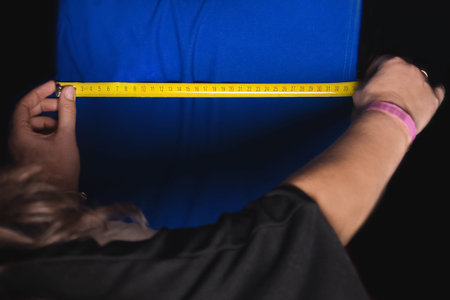 The hands of a professional seamstress measure the size of a blue vintage fabric for working with...