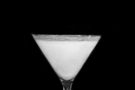 A martini glass with a white alcoholic beverage on an black background, close up.の写真素材