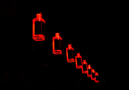 Red bottles with neon light element interior on a black background.の写真素材