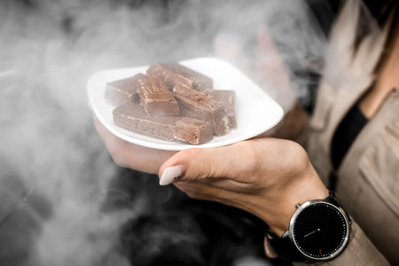 The girl attracts attention by holding in her hand a white saucer with pieces of chocolate in the...