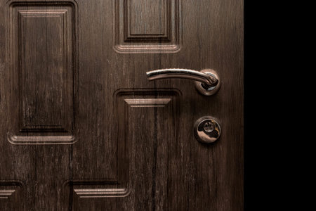 Steel doorknob brown wooden opening closing entrance exit house home isolated black object close-up.