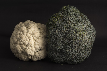 Couple of cauliflower and broccoli on a dark background, with theatrical lighting. Fresh vegetables. Dark cauliflower.の写真素材