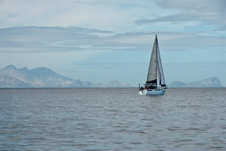 The view of a sail boat on calm waters, with mountains in the back, Cape Town, South Africaの写真素材