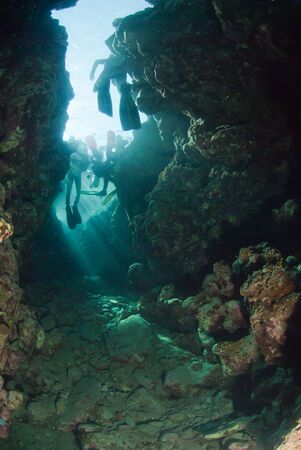 The view of scubadivers swimming through an opening towards sunlight, Dahab, Egyptの写真素材