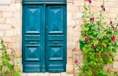 traditional cypriot front door with blooming malva flowersの写真素材