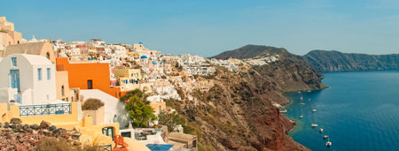 paroramic view of famous Greek city of Oia with beautiful terraces and white houses with mountains...