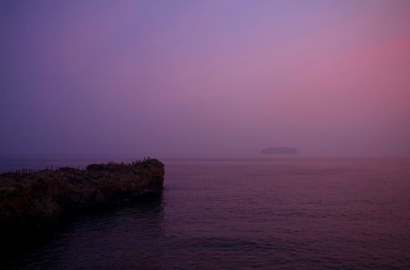 rocks with walking trail on it in dusk with view of another island in distanceの写真素材
