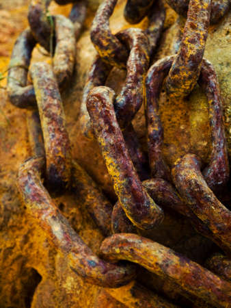 three rusty chains on rockの写真素材