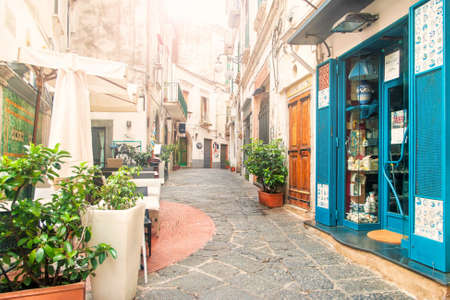 VIETRI-SUL-MARE, ITALY - 3 SEPTEMBER, 2017: view of empty narrow street full of cafes and souvenir shops in early morning with sun shining through the buildingsのeditorial素材