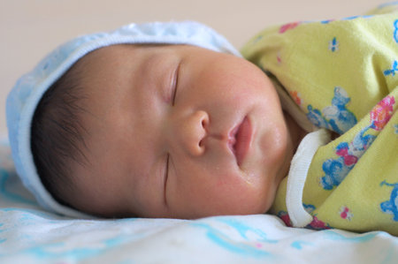 Newborn baby in bonnet is sleeping