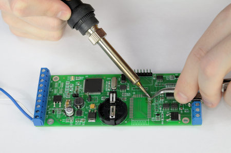 Repair pc board of device with a soldering iron and tweezers