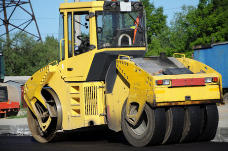 Yellow rolling machinery working and paving asphalt