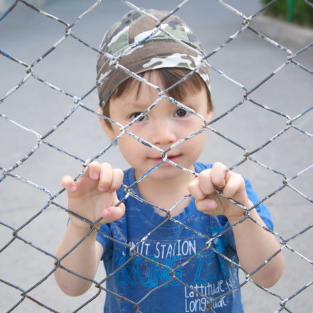 Caucasian boy looking through the bars outdoor