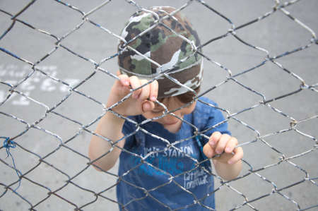 Caucasian boy behind the bars looking down outdoorの写真素材