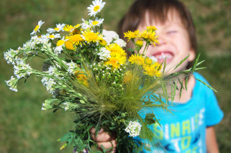Boy bringning summer bouquet of wildflowersの写真素材