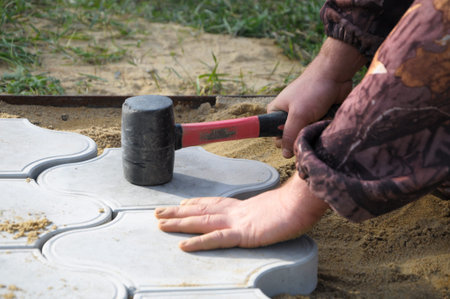 Hand of man holding hammer and installing exterior tile