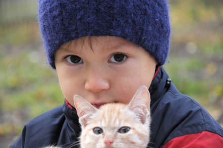Boy portrait in warm clothes hugging little kittenの写真素材
