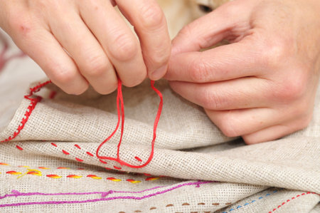 Woman hands sewing with floss needle and thread