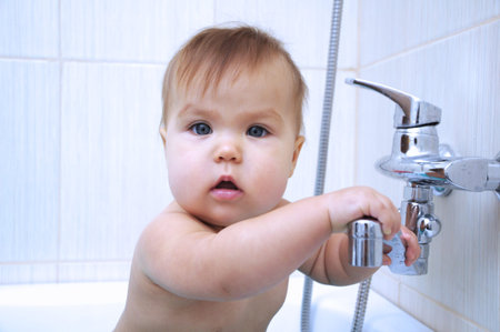 Baby girl in the bathroom holding washstand