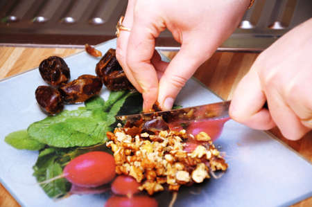 Woman hands cutting dates and walnut with knifeの写真素材