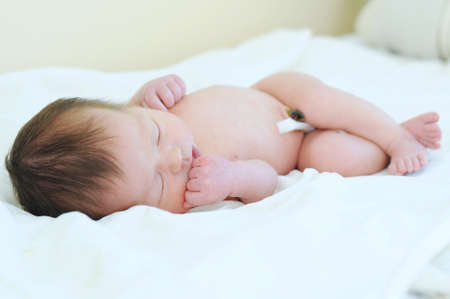 Newborn baby with umbilical cord sleeping undressedの写真素材