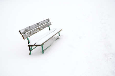 single snowy bench outdoor surrounded with white snowの写真素材