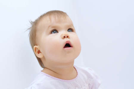 Baby girl looking up at gray backgroundの写真素材