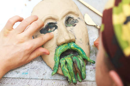 Man sculpting plasticine form of face with moustacheの写真素材