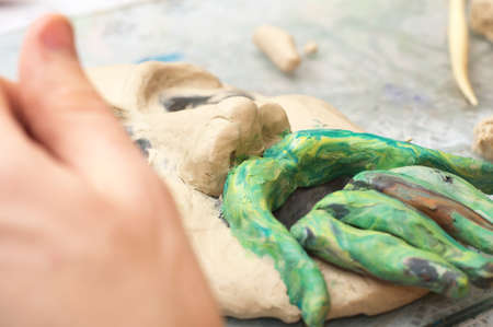 Hands sculpting craft with plasticine the form of face with moustacheの写真素材