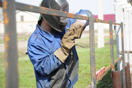 welder outdoor working and hammering iron with mask