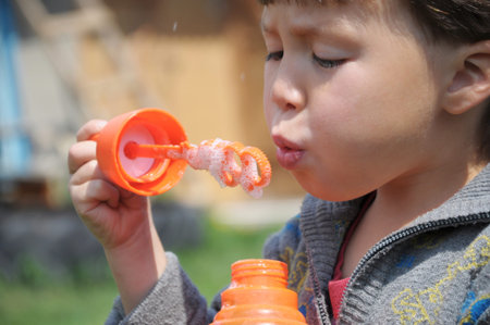 Child blowing the soap bubbles at summer outside